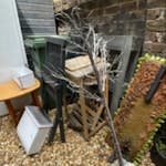 Fridge Freezer and others Fridge Freezer, might work. Two wooden tables. Garden chairs. Pine indoor chair, recyclable? Wreath arrangement, no flowers. Pallet up-cycled outdoor plant holder. Plug in Christmas tree with LED lights. BN3